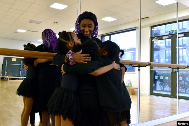 Maya, 10, Kioni, 10, Keturah, 8, and Dior, 10, hug Ruth Essel, 30, founder of Pointe Black Ballet School, at the end of class in south London, Britain, January 21, 2023. (REUTERS/Alishia Abodunde)