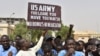 Protesters react as a man holds up a sign demanding U.S. Army soldiers leave Niger without negotiation during a demonstration in Niamey, on April 13, 2024.