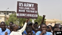 FILE - Protesters react as a man holds up a sign demanding U.S. Army soldiers leave Niger without negotiation during a demonstration in Niamey, on April 13, 2024. The U.S. will withdraw its troops from Niger, a source familiar with the matter said on Friday.