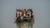 Nhân viên phòng phiếu và nhân viên an ninh đi thuyền nhỏ qua sông đến phòng phiếu ở vùng sâu vùng xa bên kia sông Brahmaputra vào đêm bầu cử quốc hội ở vùng Đông Bắc Ấn Độ, 18 tháng Tư, 2024.
