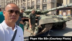 Ông Phạm Văn Bằng, bên xác một chiếc xe tăng của Nga ở Ukraine, quyết định ở lại thủ đô Kiev cùng với hàng chục người Việt khác kể từ khi Nga tiến hành xâm lược nơi ông gọi là quê hương 1 năm qua.