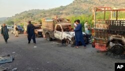 Orang-orang melihat kendaraan yang dibakar oleh kelompok bersenjata setelah membunuh penumpang, di jalan raya di Musakhail, sebuah distrik di Provinsi Baluchistan di Pakistan barat daya, Senin, 26 Agustus 2024. (Foto: AP/Rahmat Khan)