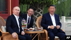 Russian President Vladimir Putin, left, and Chinese President Xi Jinping, right, attend an informal meeting in Beijing, May 16, 2024.
