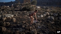 FILE - Jaquelin Stocklein of Germany drops water to a burnt area during a wildfire near the seaside resort of Lindos, on the Aegean Sea island of Rhodes, southeastern Greece, on July 24, 2023.