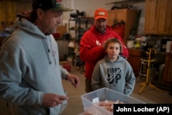 Kelly Martin (L) prepares walleye for cooking as Anthony Martin (C) and his son Caleb Ryan watch, April 19, 2024, in Hayward, Wis. (AP Photo/John Locher)