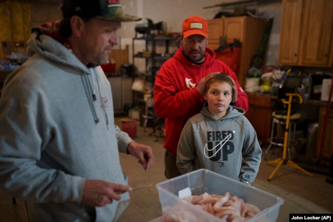 Kelly Martin (L) prepares walleye for cooking as Anthony Martin (C) and his son Caleb Ryan watch, April 19, 2024, in Hayward, Wis. (AP Photo/John Locher)