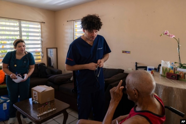 Dr. Pedro Juan Vázquez, better known by his stage name PJ Sin Suela, attends to a patient in Loiza, Puerto Rico, Saturday, May 25, 2024. (AP Photo/Alejandro Granadillo)