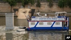 A ship sails past reproductions of artworks decorating the banks of the River Seineat the 2024 Summer Olympics, Tuesday, July 30, 2024, in Paris, France. (AP Photo/Vadim Ghirda)
