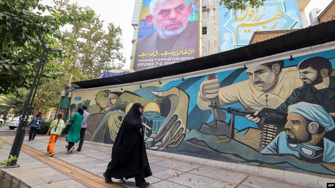 La gente pasa junto a una valla publicitaria que muestra un retrato del recién nombrado líder de Hamás, Yahya Sinwar (arriba), junto a la Plaza Palestina en Teherán, el 12 de agosto de 2024.