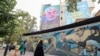 People walk past a billboard showing a portrait of newly appointed Hamas leader Yahya Sinwar (top) next to Palestine Square in the Tehran, Aug. 12, 2024. 