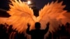 A reveler is silhouetted against a pair of angel wings as they help a performer with a costume during a Gay Pride parade marking the culmination of LGBTQ+ Pride month, in Asuncion, Paraguay, June 29, 2024. 