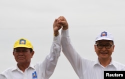 FILE: Cambodia National Rescue Party (CNRP) president Sam Rainsy (R) and vice president Kem Sokha greet their supporters in Kampong Speu province July 20, 2013.