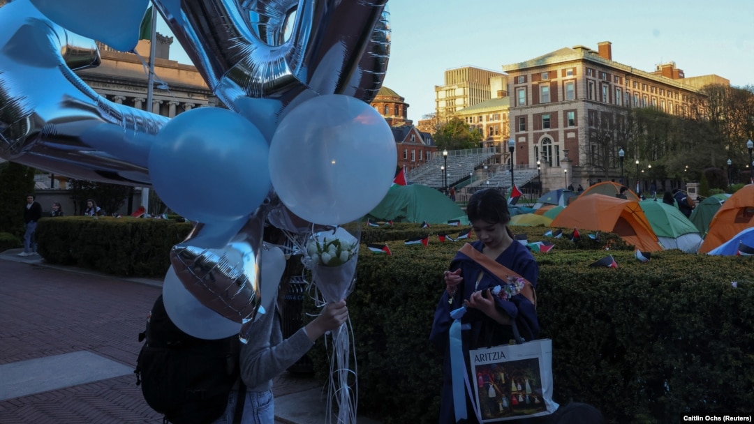 Siswa membawa balon dan mengenakan gaun untuk foto wisuda sementara siswa lainnya terus melakukan aksi protes pro- Palestina di Universitas Columbia di New York City, AS, 26 April 2024. (Foto: REUTERS/Caitlin Ochs)