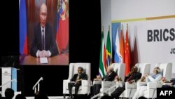 Presiden Rusia Vladimir Putin (tampak di layar monitor) memberikan pidato di KTT BRICS melalui rekaman video, Selasa (22/8).