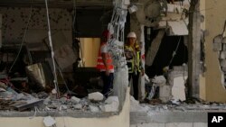 Municipality workers inspect the damage to an apartment building a day after it was hit by a rocket fired from the Gaza Strip, in Rehovot, Israel, May 12, 2023.