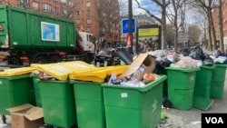 A garbage truck sails by piled-up litter in Paris. Collectors have been striking for more than two weeks now. (Lisa Bryant/VOA)