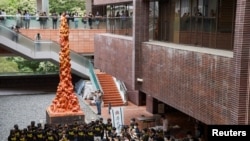 資料照片: 2021年6月4日，學生在香港大學的“國殤之柱”前默哀一分鐘，以紀念 1989年在中國香港天安門廣場鎮壓民主示威者32週年。