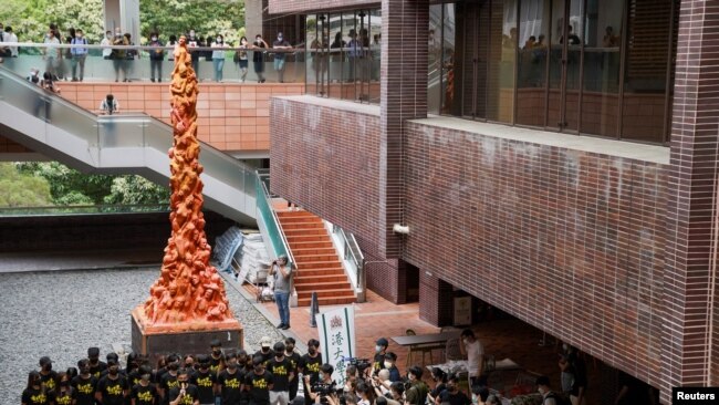 资料照片: 2021年6月4日，学生们在香港大学的“国殇之柱”前默哀一分钟，以纪念 1989年在中国香港天安门广场镇压民主示威者32周年。