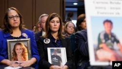 FILE - People hold photos of their children during a Senate Judiciary Committee hearing on online safety for children, Feb. 14, 2023, on Capitol Hill in Washington. 