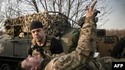 A wounded Ukrainian seviceman flashes the V-sign as he is carried away from the front line near Bakhmut, March 23, 2023.