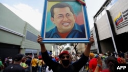 A supporter of President Nicolas Maduro holds a portrait of the late Venezuelan president, Hugo Chavez, as he takes part in a march to defend the Law against Fascism, Neofascism and Similar Expressions in Caracas on Aug. 23, 2024.