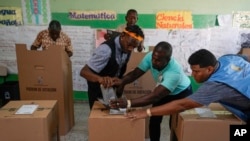 Election workers help a voter cast his ballot during general elections in Santo Domingo, Dominican Republic, May 19, 2024.