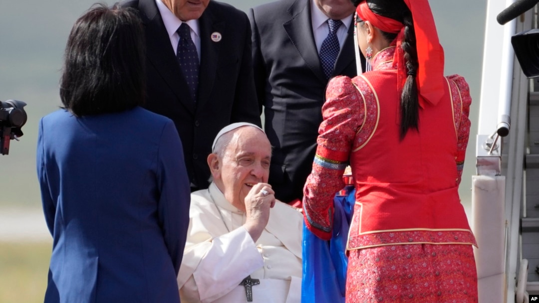 Pope Francis picks up a piece of aaruul or Mongolian curd cheese as he arrives at Ulaanbaatar's international airport Chinggis Khaan, Sept. 1, 2023. 