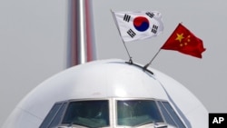 FILE - With national flags of South Korea, left, and China, a Boeing 747 arrives at Beijing Capital International Airport, June 27, 2013.