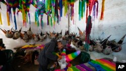 A worker makes a traditional Christmas "piñata" that will filled with fruit and candy at a family-run piñata-making business in Acolman, just north of Mexico City, Dec. 13, 2023.