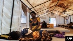 FILE - Modester Patrick holds the hand of her son at a temporary cholera treatment centre at Bwaila District hospital in Lilongwe, Malawi, Feb. 21, 2023