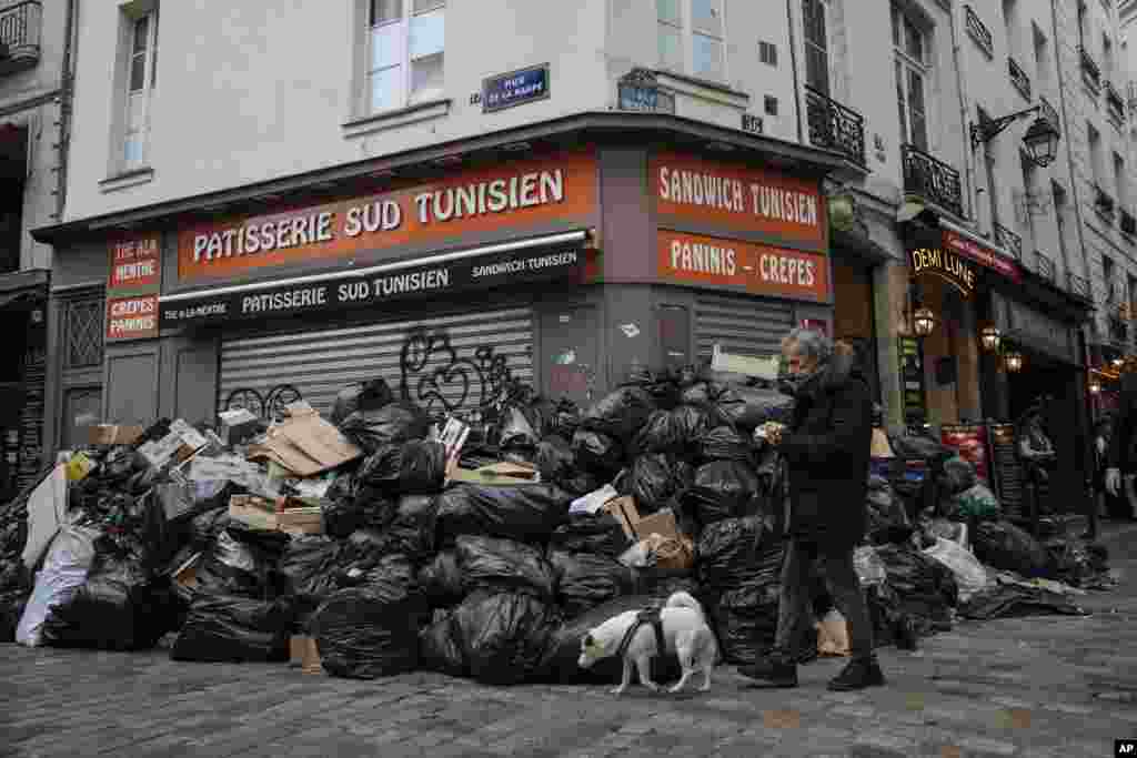A man walks past piles of garbage in Paris, France.&nbsp;A contentious bill that would raise the retirement age in France from 62 to 64 got a push forward with the Senate&#39;s adoption of the measure amid strikes, protests and uncollected garbage piling higher by the day.&nbsp;