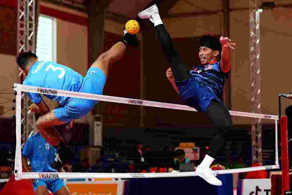 Malaysia's Muhammad Hafizul Adnan, right, vies for the ball with Cambodia's Phom Kongkia during their men's sepaktakraw, or kick volleyball, team match at the 32nd Southeast Asian Games in Phnom Penh.