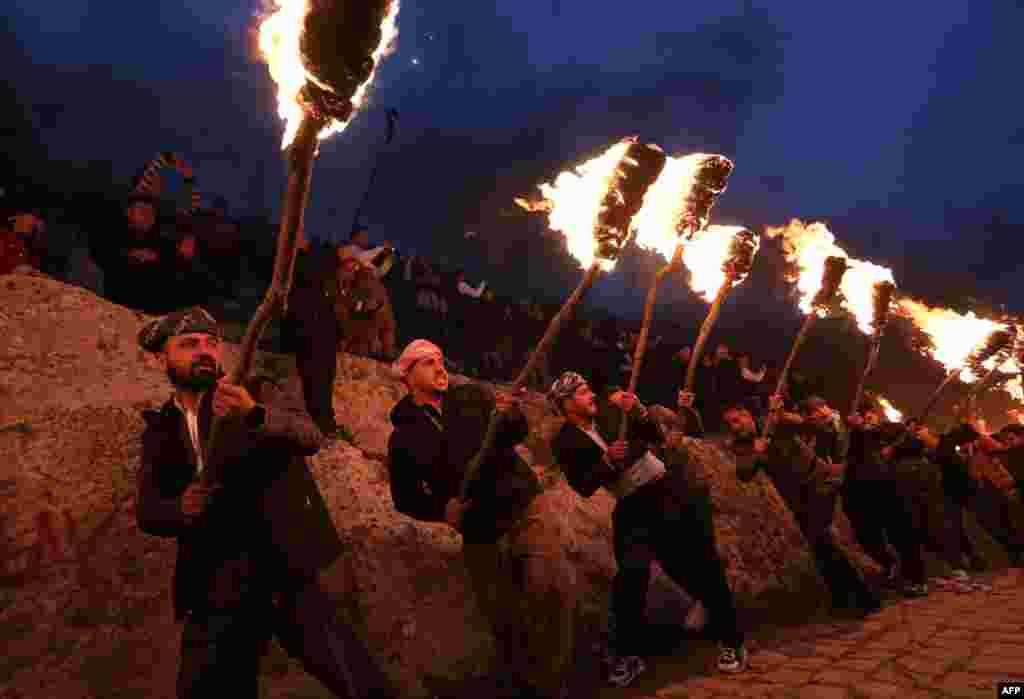 Ирачките Курди држејќи факели одат по планина за време на поворка за да го прослават својот Новогодишен фестивал на Новруз во Акре.