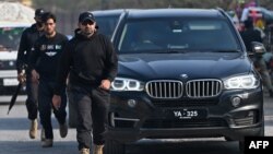 Security personnel escort a vehicle carrying Bushra Bibi, wife of jailed former Pakistan's Prime Minister Imran Khan, as she arrives at Adiala Jail in Rawalpindi on Dec. 12, 2023, before her husband's hearing at a special court. 