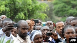 Wakenya wakitumia simu zao za mkononi kufuatilia na kurekodi mazishi ya mwanamazingira na mshindi wa tuzo ya amani, Wangari Maathai, tarehe 8 Oktoba 2011. Picha na SIMON MAINA / AFP.