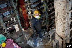 Pekerja membersihkan balok beton yang rusak untuk diproses ulang di jalur produksi balok yang dibuat dengan karbon dioksida cair sebagai bahan di Glenwood Mason Supply Company, di wilayah Brooklyn, New York, 18 April 2023. (Foto AP/John Minchillo)