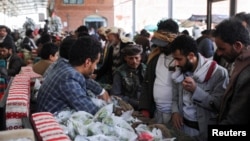 FILE - Customers crowd around a seller's display at a market in Sanaa, Yemen, May 15, 2024.