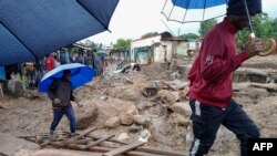 People cross a makeshift bridge over floodwaters in Chimkwankhunda in Blantyre on March 14, 2023, following Cyclone Freddy's landfall. 