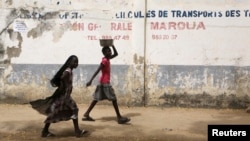 FILE - Girls walk on a road in Maroua, Cameroon, March 17, 2016. Cameroon’s government says 70% of menstruating women and girls lack access to regular basic sanitation products. 