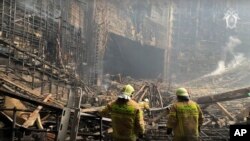 In this photo taken from a video released by the Russian Investigative Committee on March 23, 2024, firefighters work at the burned concert hall after the attack on the Krokos City Hall building on the western edge of Moscow.
