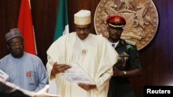 FILE - Nigeria's President Muhammadu Buhari looks at a sample of the new N1,000 note, November 23, 2022.