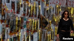 A woman walks past yellow ribbons and posters with images of hostages kidnapped in the deadly October 7 attack on Israel by the Palestinian Islamist group Hamas, in Tel Aviv, Israel, April 10, 2024.