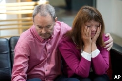 FILE - Simon Glass, left, and his wife, Sally, embrace as they talk during a news interview in the offices of the couple's lawyers in Denver, May 23, 2023.