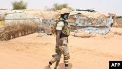 FILE- Nigerien soldier patrols as United Nations Secretary-General Antonio Guterres (not seen) visits an internally displaced persons (IDP) camp in Ouallam, Niger, on May 3, 2022 