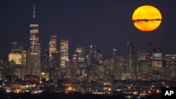 FILE - The moon rises through clouds over the skyline of lower Manhattan in this view from West Orange, N.J., Aug. 1, 2023, during a supermoon period. 