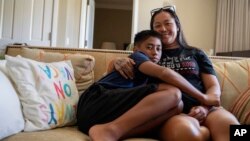 Puʻuwai Nahoʻoikaik, left, leans on his mother, Tiffany Teruya, for a portrait at their temporary housing at Honua Kai Resort, Oct. 3, 2023, in Lahaina, Hawaii.