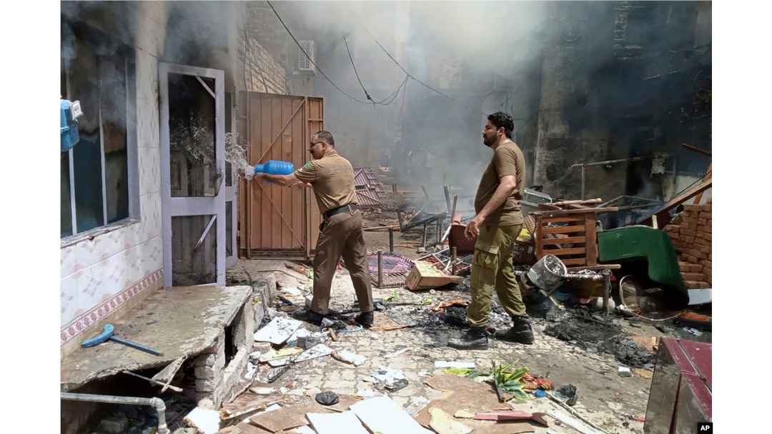 In this photo provided by district police office, a police officer puts out a fire in a burning house at a Christian neighborhood following an angry mob attack in Jaranwala near Faisalabad, Pakistan, Aug. 16, 2023.