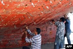 Workers restore a traditional wooden ship, called a lenj, in a shipyard on Iran's Qeshm island in the Gulf, on April 29, 2023.