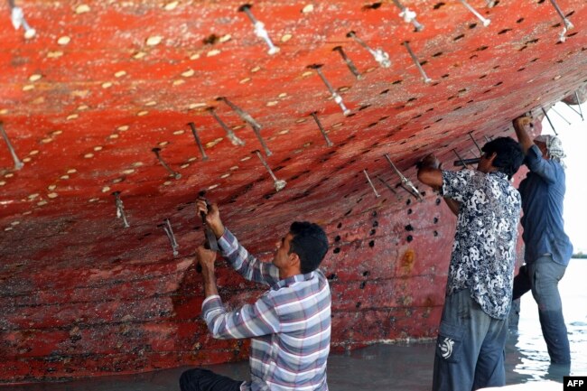 Workers restore a traditional wooden ship, called a lenj, in a shipyard on Iran's Qeshm island in the Gulf, on April 29, 2023.