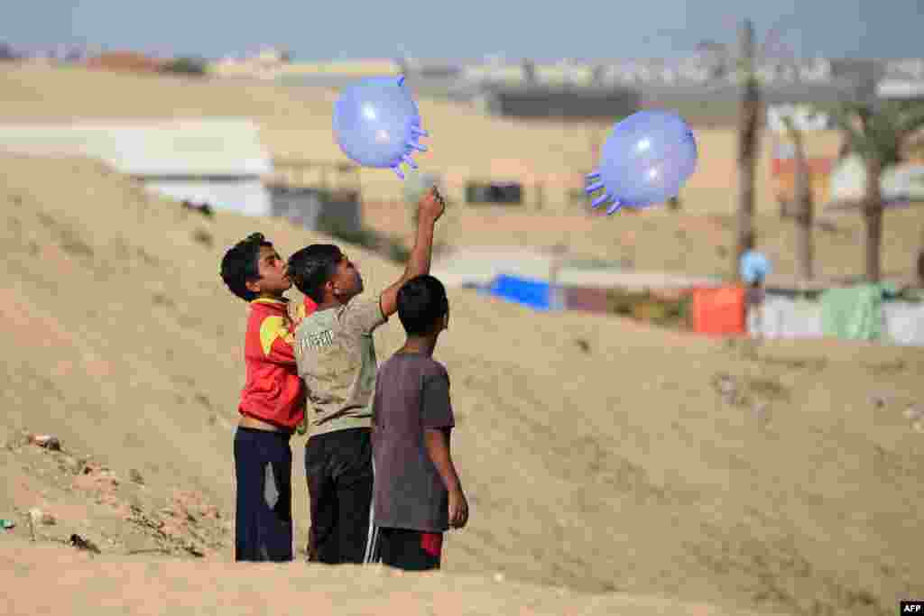 Displaced Palestinian children play with surgical rubber gloves in Rafah in the southern Gaza Strip.
